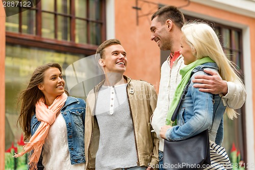 Image of group of smiling friends walking in the city