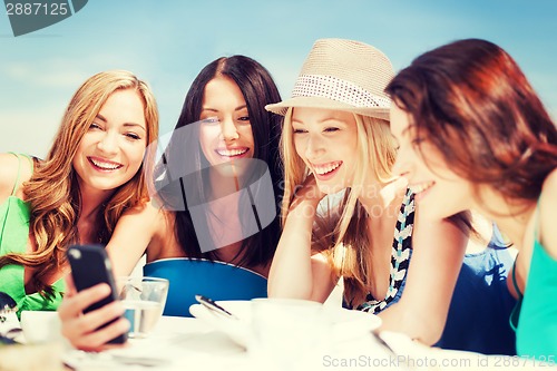 Image of girls looking at smartphone in cafe on the beach