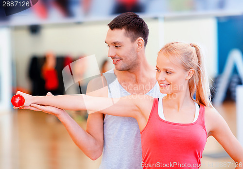 Image of male trainer with woman working out with dumbbell