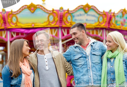 Image of group of smiling friends in amusement park