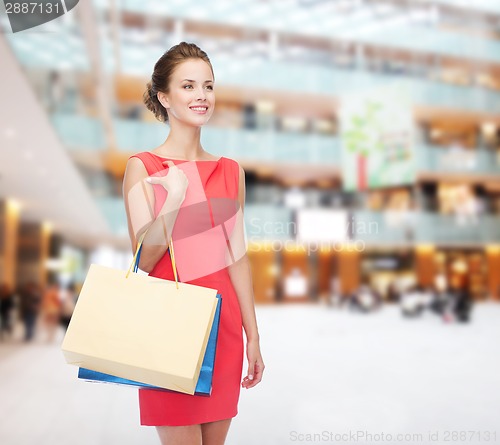 Image of smiling elegant woman in dress with shopping bags