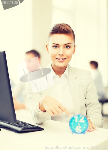 Image of businesswoman pointing at clock in office