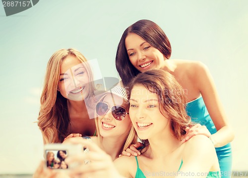 Image of smiling girls taking photo in cafe on the beach