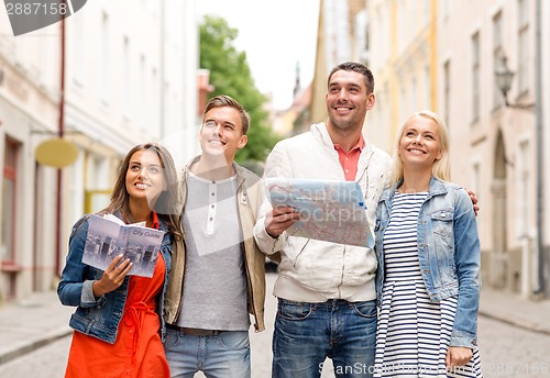 Image of group of smiling friends with city guide and map