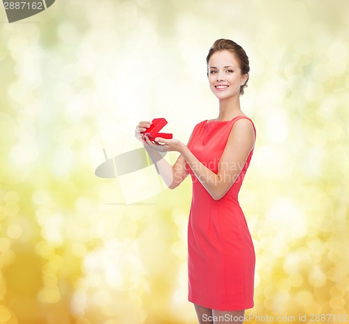 Image of smiling young woman in red dress with gift box