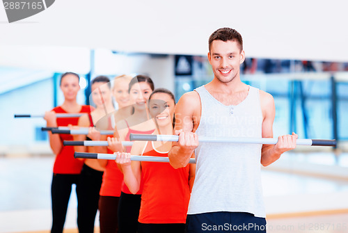 Image of group of smiling people working out with barbells
