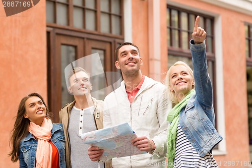 Image of group of smiling friends with map exploring city