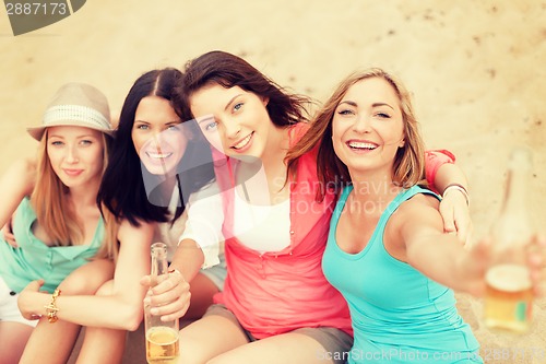 Image of smiling girls with drinks on the beach