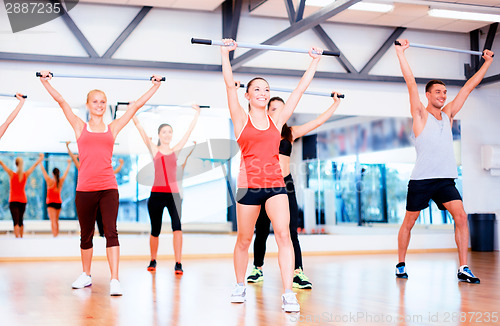 Image of group of smiling people working out with barbells