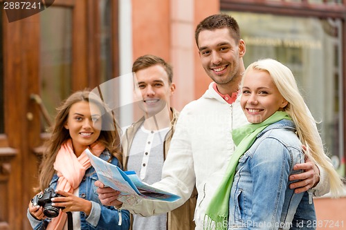 Image of group of smiling friends with map and photocamera