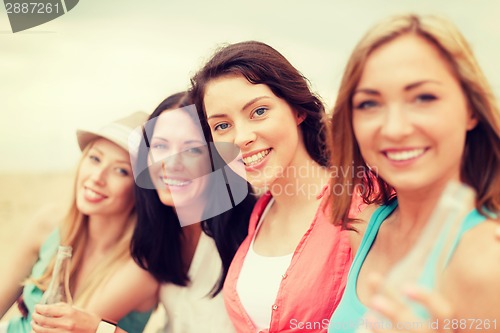 Image of smiling girls with drinks on the beach