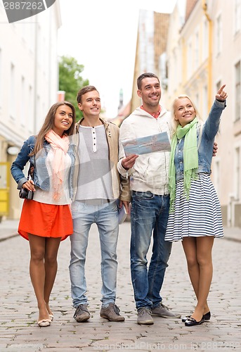 Image of group of smiling friends with map and photocamera