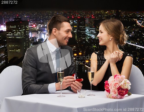 Image of man proposing to his girlfriend at restaurant