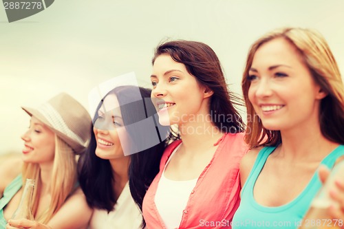 Image of smiling girls with drinks on the beach