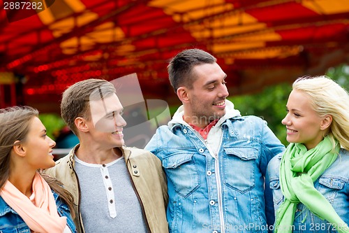 Image of group of smiling friends in amusement park