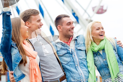 Image of group of smiling friends in amusement park