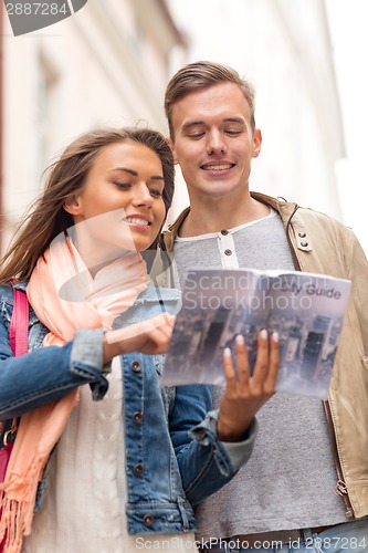 Image of smiling couple with city guide exploring town