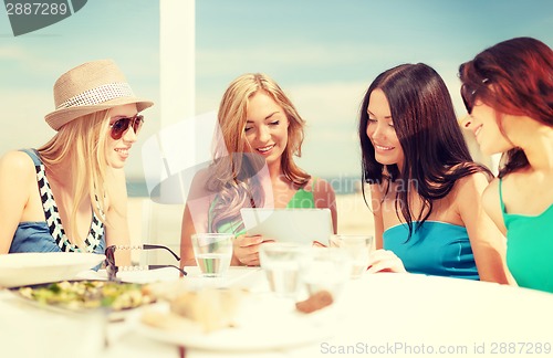 Image of smiling girls looking at tablet pc in cafe