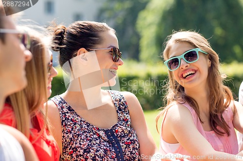 Image of group of smiling friends outdoors sitting in park