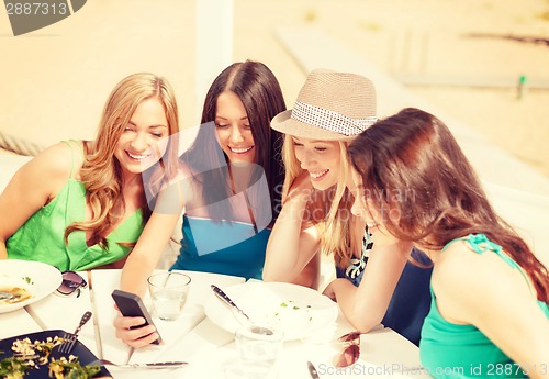 Image of girls looking at smartphone in cafe on the beach