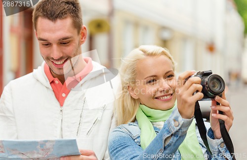 Image of smiling couple with map and photocamera in city