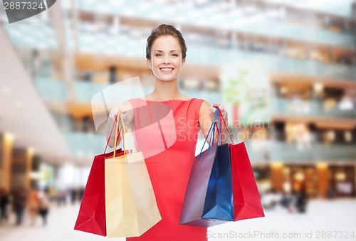 Image of smiling elegant woman in dress with shopping bags