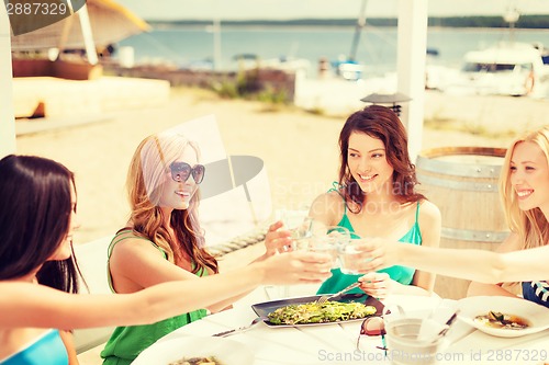 Image of smiling girls looking at tablet pc in cafe
