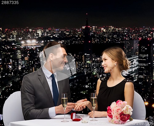 Image of man proposing to his girlfriend at restaurant