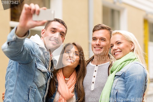 Image of group of smiling friends making selfie outdoors