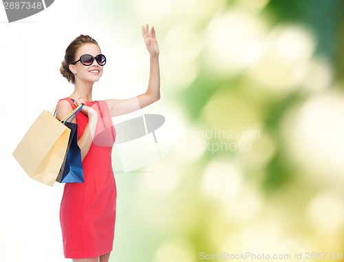 Image of smiling elegant woman in dress with shopping bags