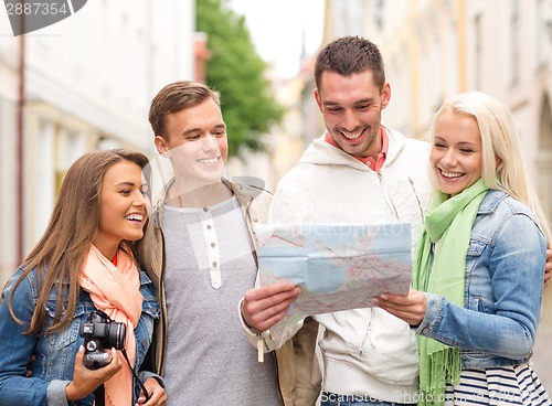 Image of group of smiling friends with map and photocamera