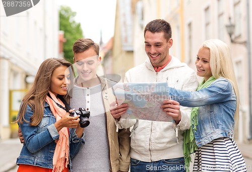 Image of group of smiling friends with map and photocamera