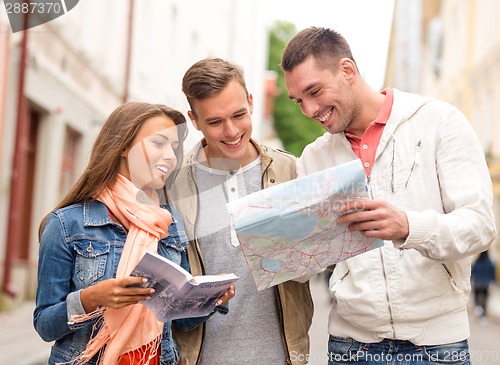 Image of group of smiling friends with city guide and map