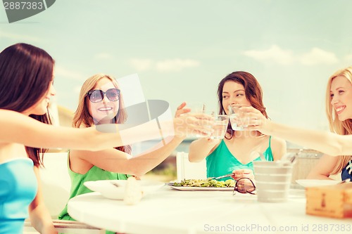 Image of smiling girls looking at tablet pc in cafe