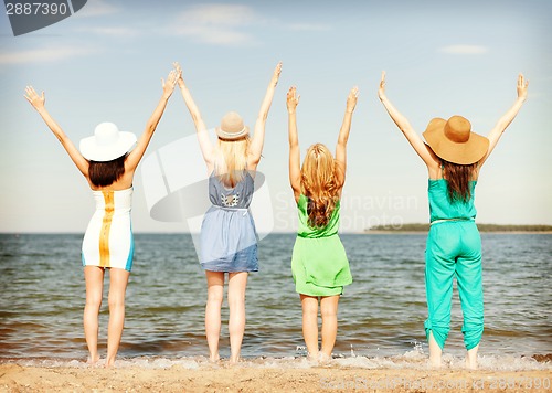 Image of girls with hands up on the beach