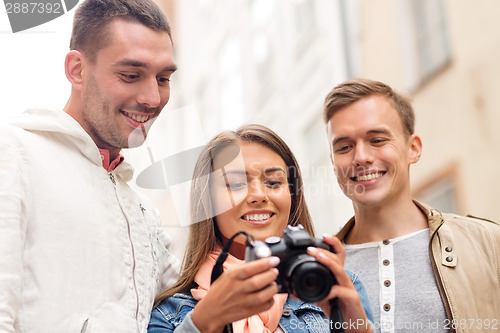 Image of group of smiling friends with digital photocamera