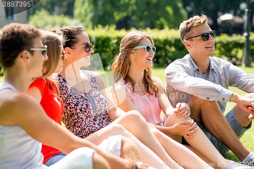 Image of group of smiling friends outdoors sitting on grass