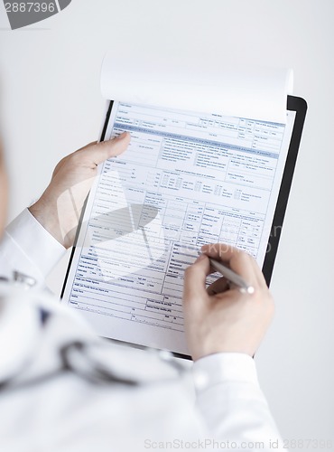 Image of male doctor holding prescription paper in hand