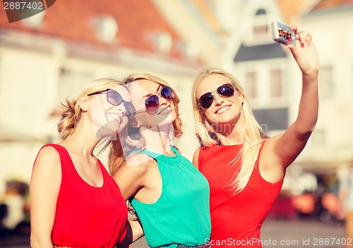Image of three beautiful girls taking picture in the city