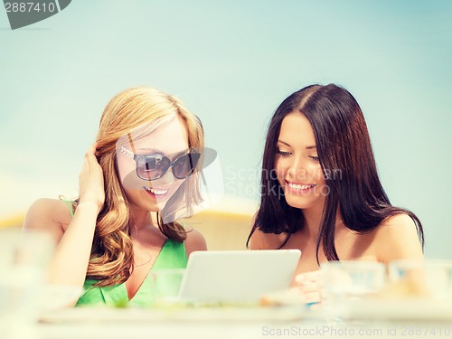 Image of smiling girls looking at tablet pc in cafe