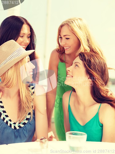 Image of group of smiling girls in cafe on the beach