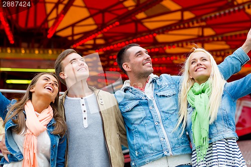 Image of group of smiling friends in amusement park