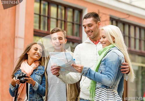Image of group of smiling friends with map and photocamera