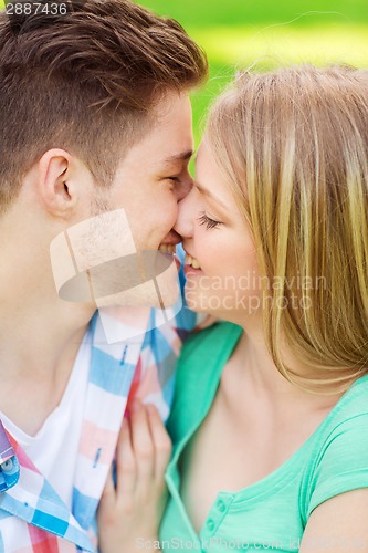 Image of smiling couple kissing and hugging in park