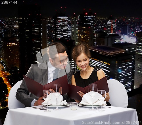 Image of smiling couple with menus at restaurant