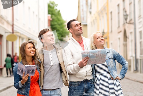 Image of group of smiling friends with city guide and map