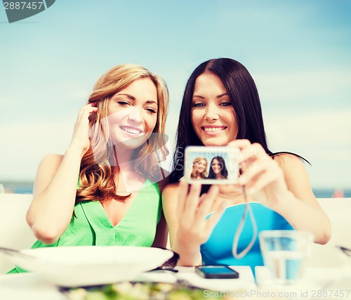 Image of girls taking photo in cafe on the beach