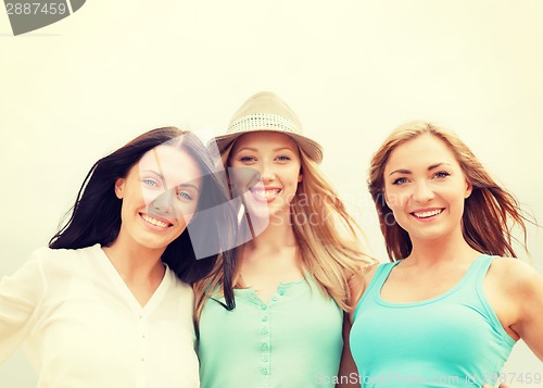 Image of group of smiling girls chilling on the beach