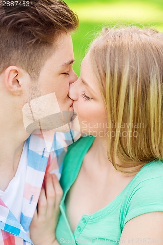 Image of smiling couple kissing and hugging in park