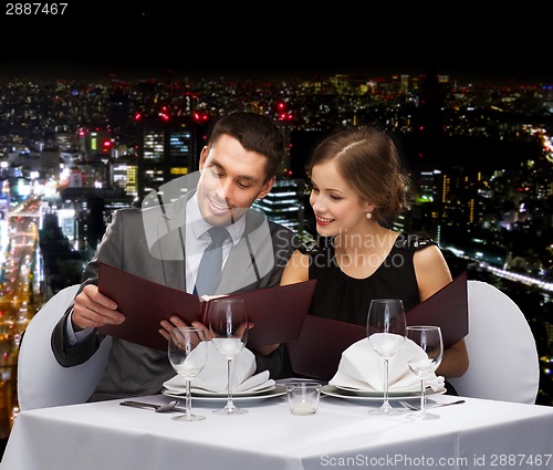 Image of smiling couple with menus at restaurant